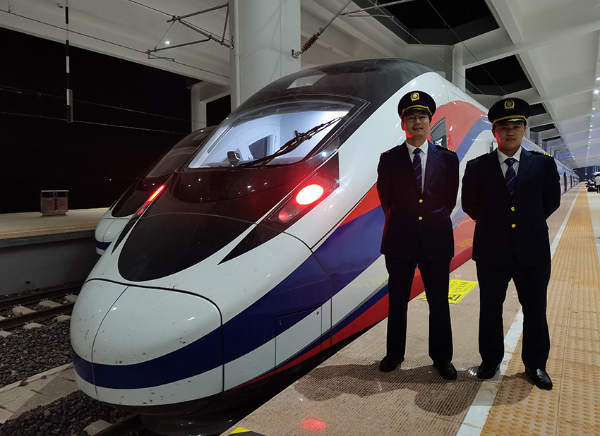 刘银能(右一)与中国师父邬俊鸿在动车组前合影。受访者供图